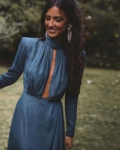 a woman in a blue dress is smiling and holding her hand out to the side