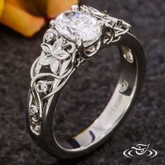 a close up of a ring on a table with fruit in the background and an apple behind it