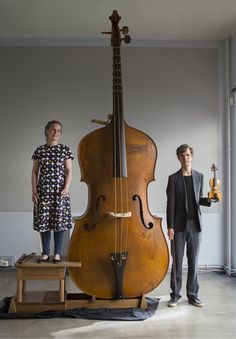 two women standing next to a large instrument