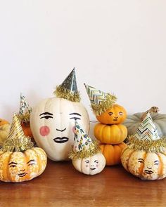 several pumpkins with faces painted on them sitting on a wooden table next to other pumpkins