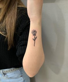 a woman's arm with a single rose tattoo on the left side of her arm