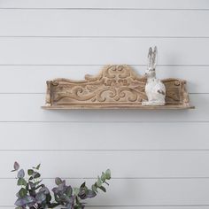 a wooden shelf with a bunny figurine on it next to a potted plant