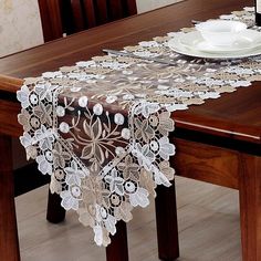 the table is set with white plates and silverware on it, along with a lace doily