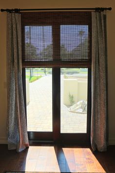 an open window with curtains and blinds on the outside, in front of a sliding glass door