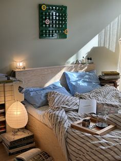 an unmade bed in a bedroom with blue sheets and striped comforter on it