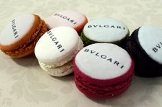 four different colored macarons with words written on them sitting next to each other