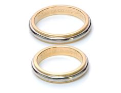 two gold and silver rings on a white surface with the words,'love is in the air '