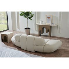 a white couch sitting on top of a wooden floor next to a table with a potted plant