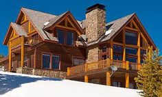 a large log home on top of a snow covered hill