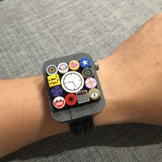 a person's arm with an apple watch covered in stickers and magnets