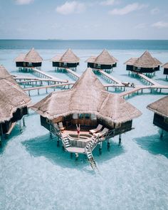 the water is crystal blue and clear with some huts on it's sides in the ocean