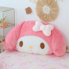 a pink hello kitty stuffed animal sitting on top of a bed next to a wall