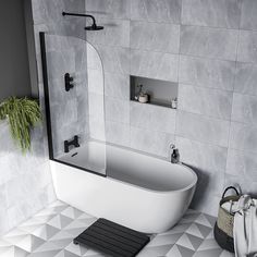 a white bath tub sitting on top of a tiled floor next to a planter