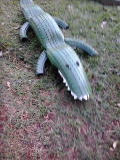 a fake alligator laying on the ground in the grass with it's mouth open