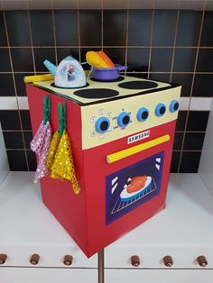 an oven made out of cardboard sitting on top of a shelf next to a tiled wall