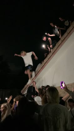 a group of people watching a skateboarder do a trick in the air at night