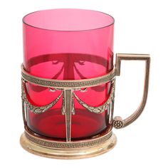 a red glass cup sitting on top of a metal stand