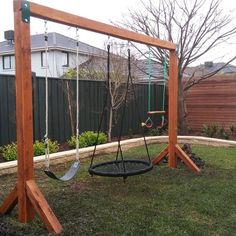 a wooden swing set with two swings in the back yard