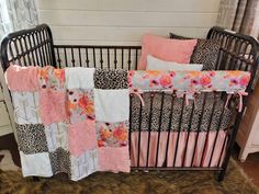 a baby crib with pink, black and white bedding