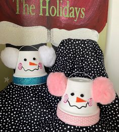 two snowmen sitting on top of a black and white polka dot covered bed next to a holiday sign