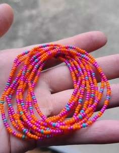 a person is holding some colorful beads in their hand and it looks like they are wearing bracelets