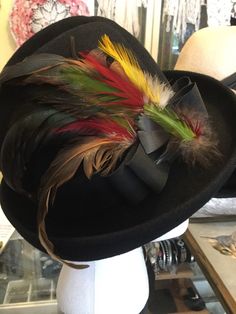 This showy hat is a class act, with its multi colored feathers and unusual shape! A show stopper. Vintage Multicolor Hats For Fall, Winter Feathered Brimmed Felt Hat, Winter Felt Hat With Feathers And Short Brim, Kentucky Derby Brimmed Felt Hat With Feather Trim, Short Brim Felt Hat With Feathers For Fall, Feathered Hats For Fall, Kentucky Derby Felt Hat With Feather Trim, Winter Felt Hat With Wide Brim And Feathers, Winter Party Hats With Feathers