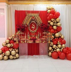 an elaborately decorated table with red and gold balloons in the shape of christmas trees