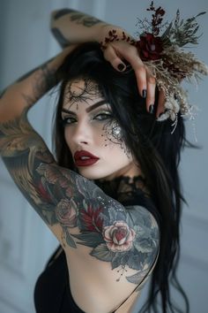 Woman with elaborate face makeup and floral tattoos posing with one hand in her hair. Female Tattoos Ideas