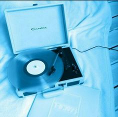 an old record player is sitting on the bed with its case open and it's plugged in