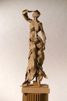 a sculpture made out of folded paper on top of a wooden block