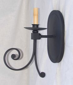 a wall mounted candle holder on the side of a white sheet with a black finish