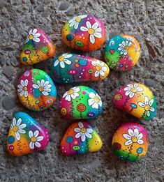 painted rocks with flowers on them sitting on the ground