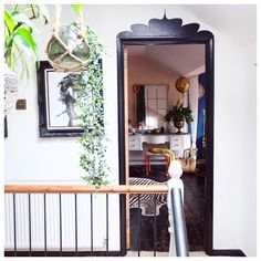 an open door leading to a living room with plants on the wall and pictures hanging above