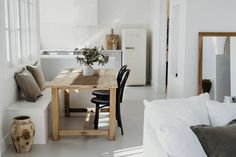 a kitchen table with chairs and a vase on it in front of a white wall