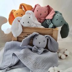 several stuffed animals in a wooden crate on a white surface with cotton balls around them