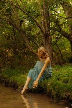 a woman sitting on the bank of a river