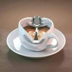 a coffee cup with saucer and spoon in the shape of a heart on a plate