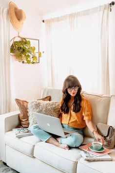 a woman sitting on a couch using a laptop computer