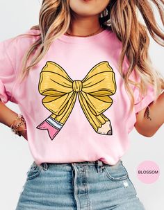 Capture the charm of school days with our "School Days Delight" T-shirt! This adorable tee features a cute bow shaped like a pencil and a retro school bus adorned with hearts on the back. Perfect for teachers, students, or anyone nostalgic for the joys of school, this shirt blends sweet and vintage vibes effortlessly. Made from soft, comfortable fabric, it's ideal for everyday wear or special occasions. Show off your love for learning and bring a touch of cuteness to your wardrobe with this delightful design! Fun Pink T-shirt For School Events, Playful Pink T-shirt For School, Pink T-shirt For End Of School Year, Pink T-shirt For Back To School, Pink Short Sleeve T-shirt For School Events, Pink School Spirit T-shirt For Back To School, Pink School Spirit T-shirt For School, Preppy Pink Tops For School, Preppy Pink Top For School