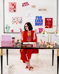 a woman sitting at a desk with her cell phone