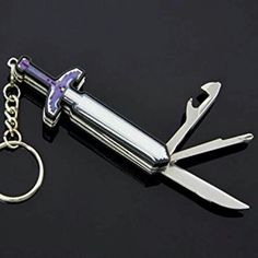 a keychain with a knife on it is laying on a black surface next to a pair of scissors