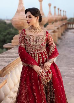 a woman in a red dress standing on a bridge