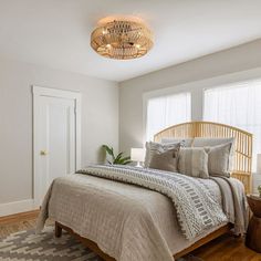 a bedroom with white walls and wood flooring has a large bed in the corner