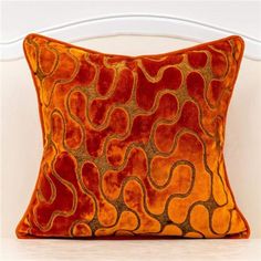 an orange and brown pillow on a white chair