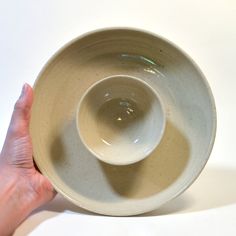 a person's hand holding a white bowl