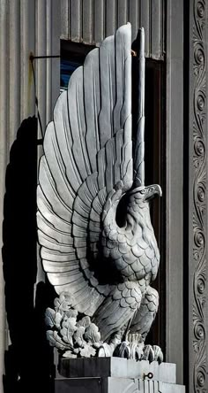 a statue of a large bird on top of a box in front of a building