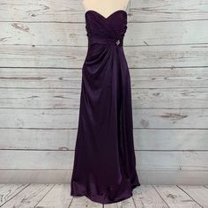 a purple bridesmaid dress on a mannequin head stand in front of a wooden wall