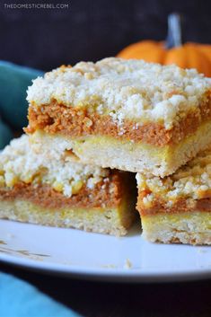 three pieces of cake sitting on top of a white plate next to an orange pumpkin