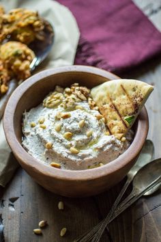 a wooden bowl filled with hummus and pita chips on top of a table