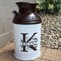 a white and brown canister with the letter k on it sitting in front of a brick wall